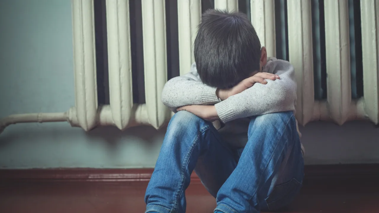 A parent sitting beside their child, helping them calm down